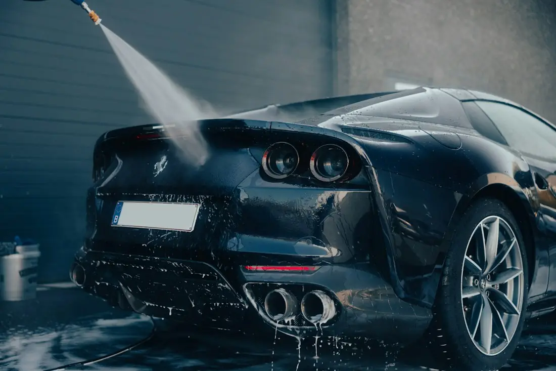 Rinsing the rear of a dark sports car