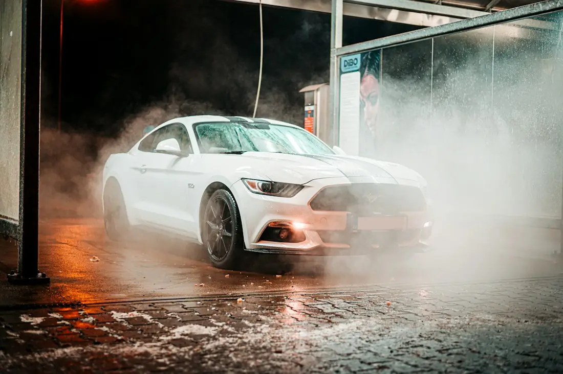 White coupe in steam at a night wash